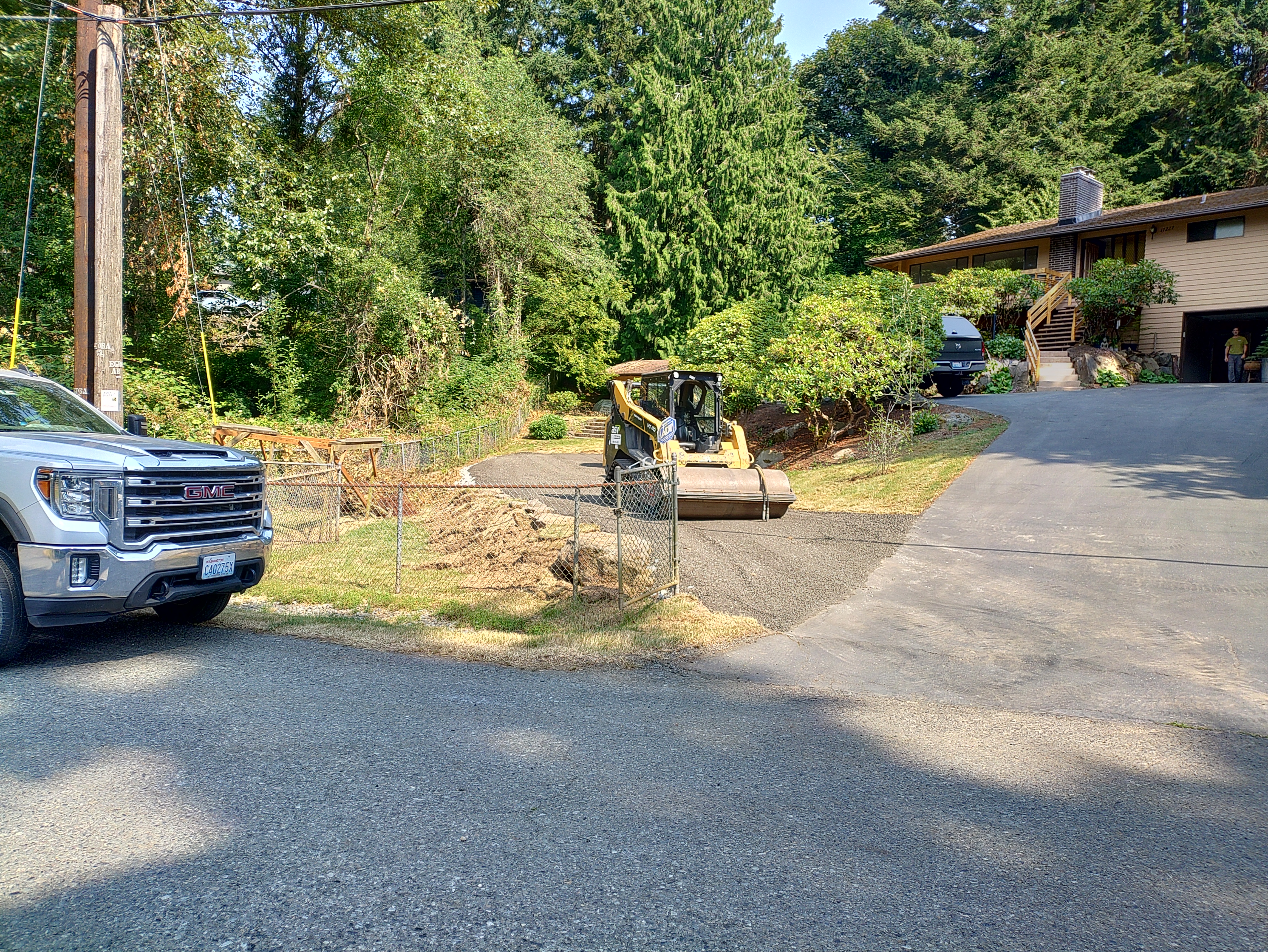 A man, likely a farmer, is driving an orange Kubota tractor with a brush cutter attachment. The man sits behind a windshie...