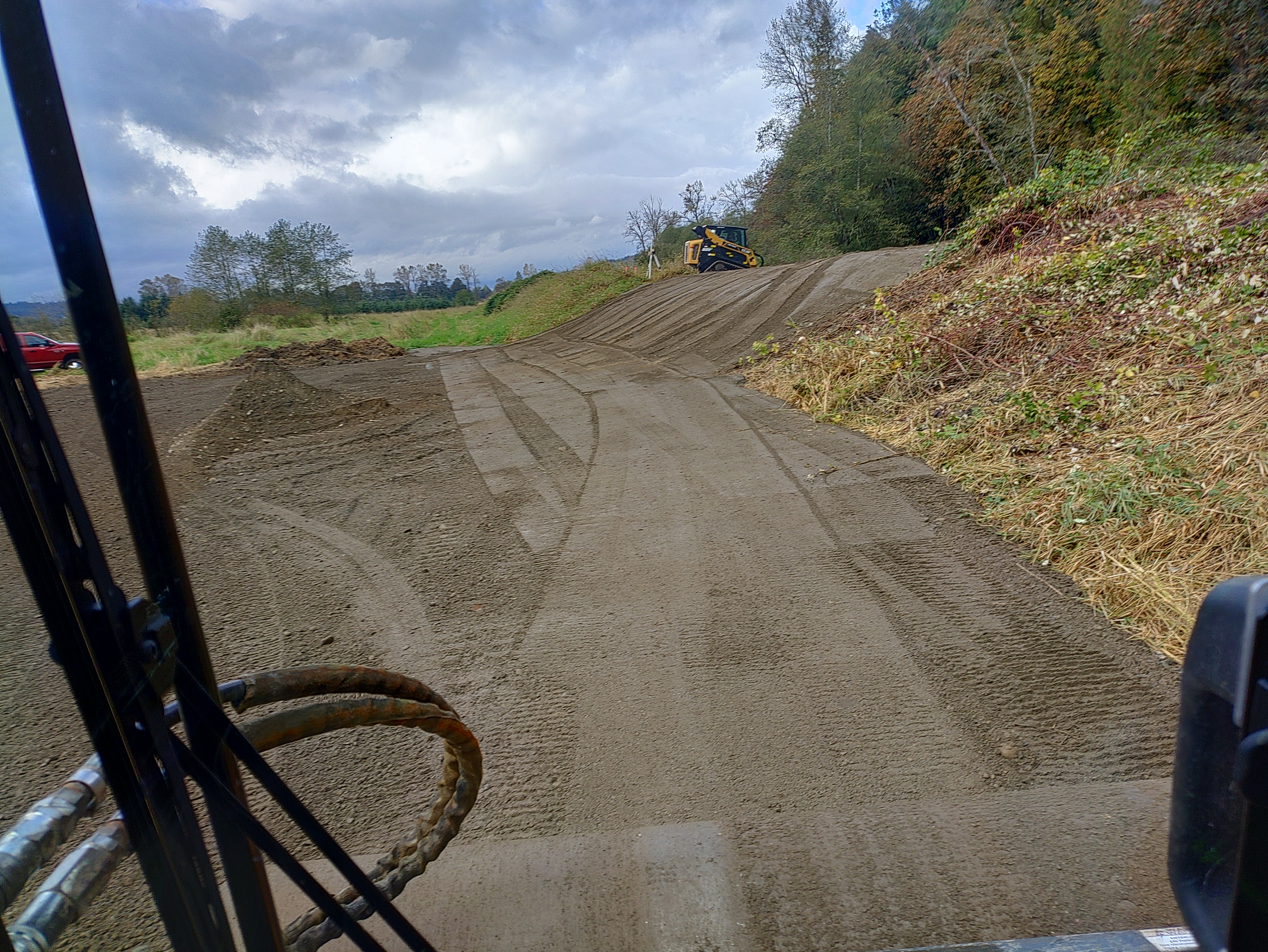 A new or empty industrial building with a flat roof and large rectangular windows, featuring dirt ground marked by tracks ...